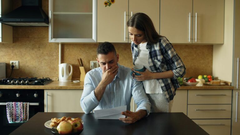 A pet owner reviews insurance papers and a veterinary bill beside a dog at a kitchen table.